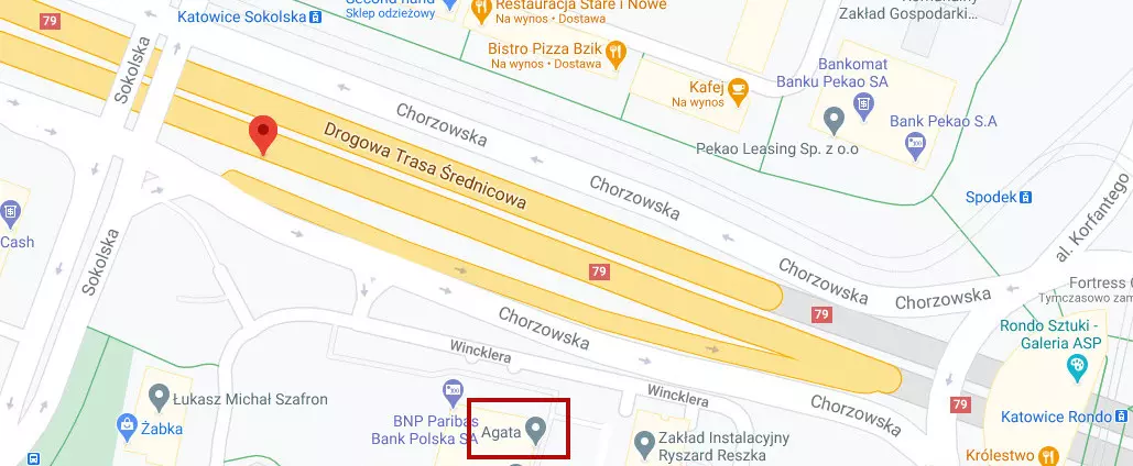 Zrzut ekranu z Google Maps. Czerwony znacznik lokalizacji wyświetla się na jezdni obok kładki, tak jak poprzednio na telefonie. Nad prostokątem (budynkiem) na południowy wschód od znacznika widać napis 'Agata'. Jest on otoczony czerwonym prostokątem.