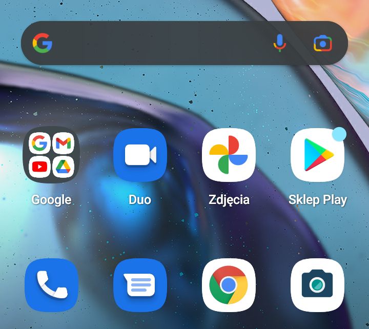 Fragment ekranu głównego smartfona. Widać tutaj pole tekstowe z logiem firmy Google, a pod nim 8 ikonek, z których większość również ma cztery firmowe kolory: niebieski, żółty, zielony i czerwony.